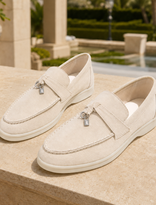 Mocassini crema slip on con punta arrotondata appoggiati su un muretto luminoso