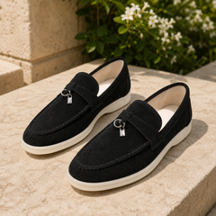 Mocassini neri slip on con pendente metallico e suola bianca tra il verde