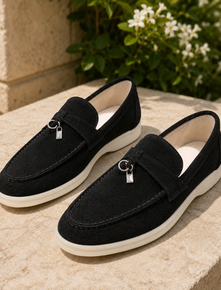 Mocassini neri slip on con pendente metallico e suola bianca tra il verde