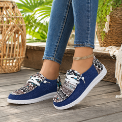 Mocassini donna blu con punta tonda e suola bianca su pavimento in legno