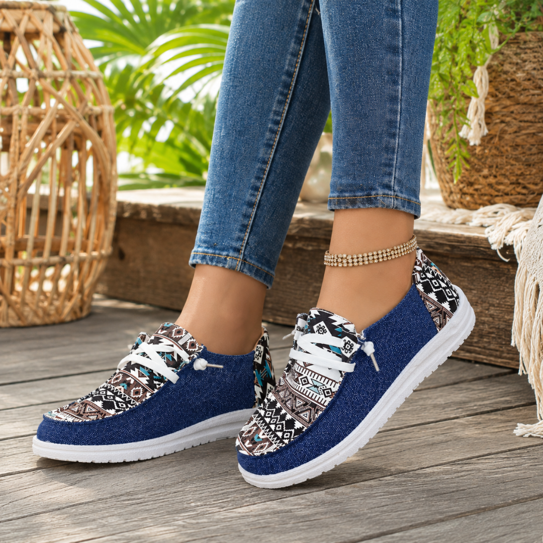 Mocassini donna blu con punta tonda e suola bianca su pavimento in legno