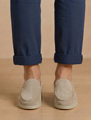 Mocassini uomo grigio chiaro dalla linea pulita, indossati con pantalone blu arrotolato