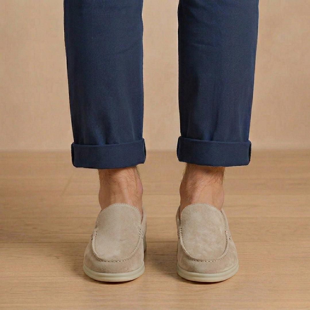 Mocassini uomo grigio chiaro dalla linea pulita, indossati con pantalone blu arrotolato