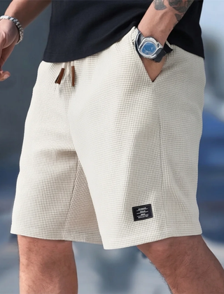 Pantaloncini uomo beige indossati in città con coulisse e piccola etichetta laterale