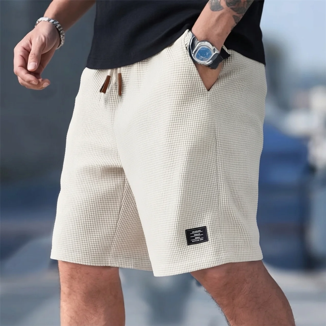 Pantaloncini uomo beige indossati in città con coulisse e piccola etichetta laterale