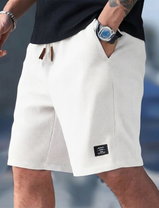 Pantaloncini uomo bianchi indossati in strada con etichetta scura sulla gamba