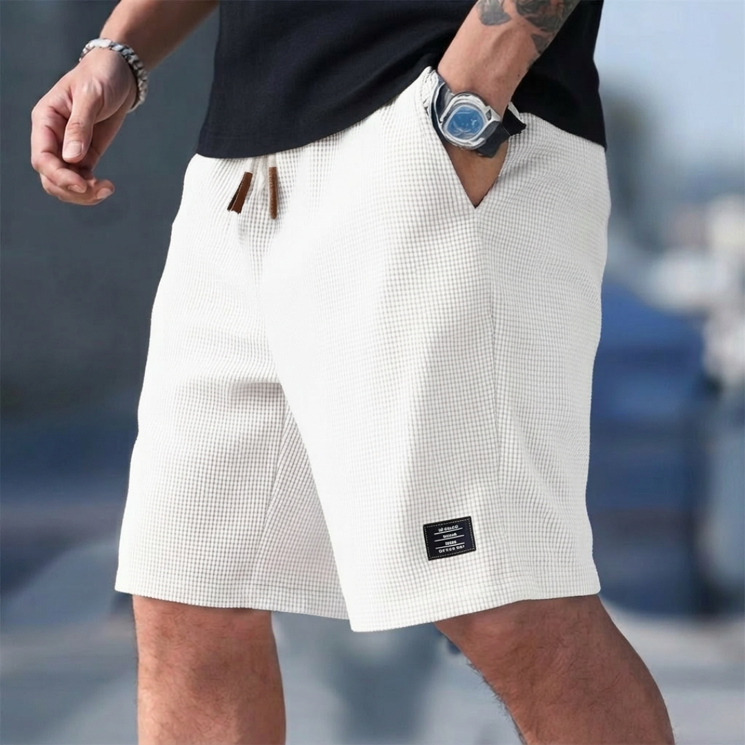 Pantaloncini uomo bianchi indossati in strada con etichetta scura sulla gamba