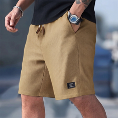 Pantaloncini uomo kaki indossati con mano in tasca e coulisse a vista