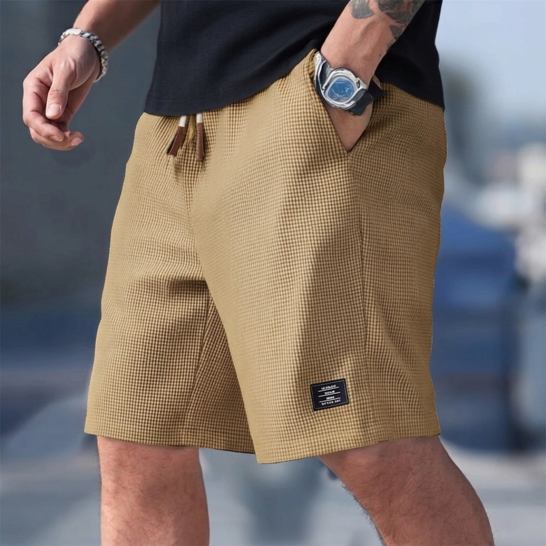 Pantaloncini uomo kaki indossati con mano in tasca e coulisse a vista