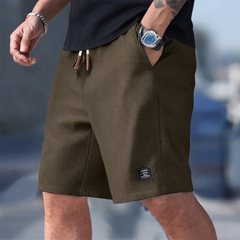 Pantaloncini uomo marroni indossati in città con tasche laterali e coulisse