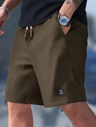 Pantaloncini uomo marroni indossati in città con tasche laterali e coulisse