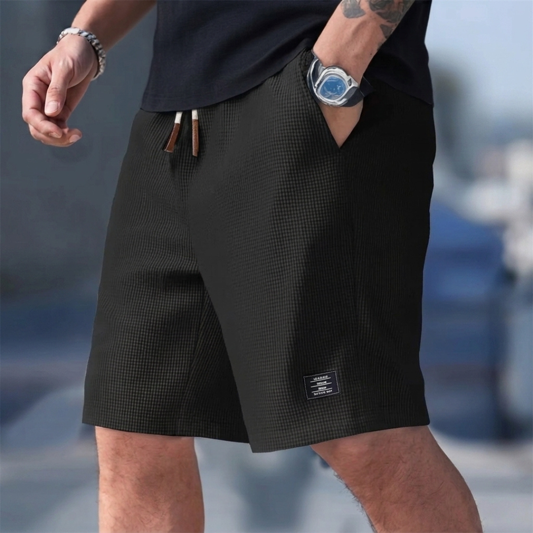 Pantaloncini uomo neri indossati con mano in tasca e coulisse a contrasto
