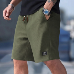 Pantaloncini uomo verde militare indossati con t-shirt nera e coulisse regolabile