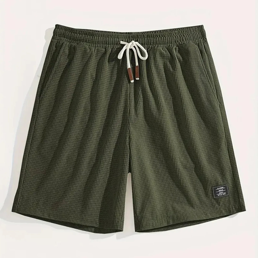 Pantaloncini verde militare distesi con laccio chiaro annodato ed etichetta sul lato