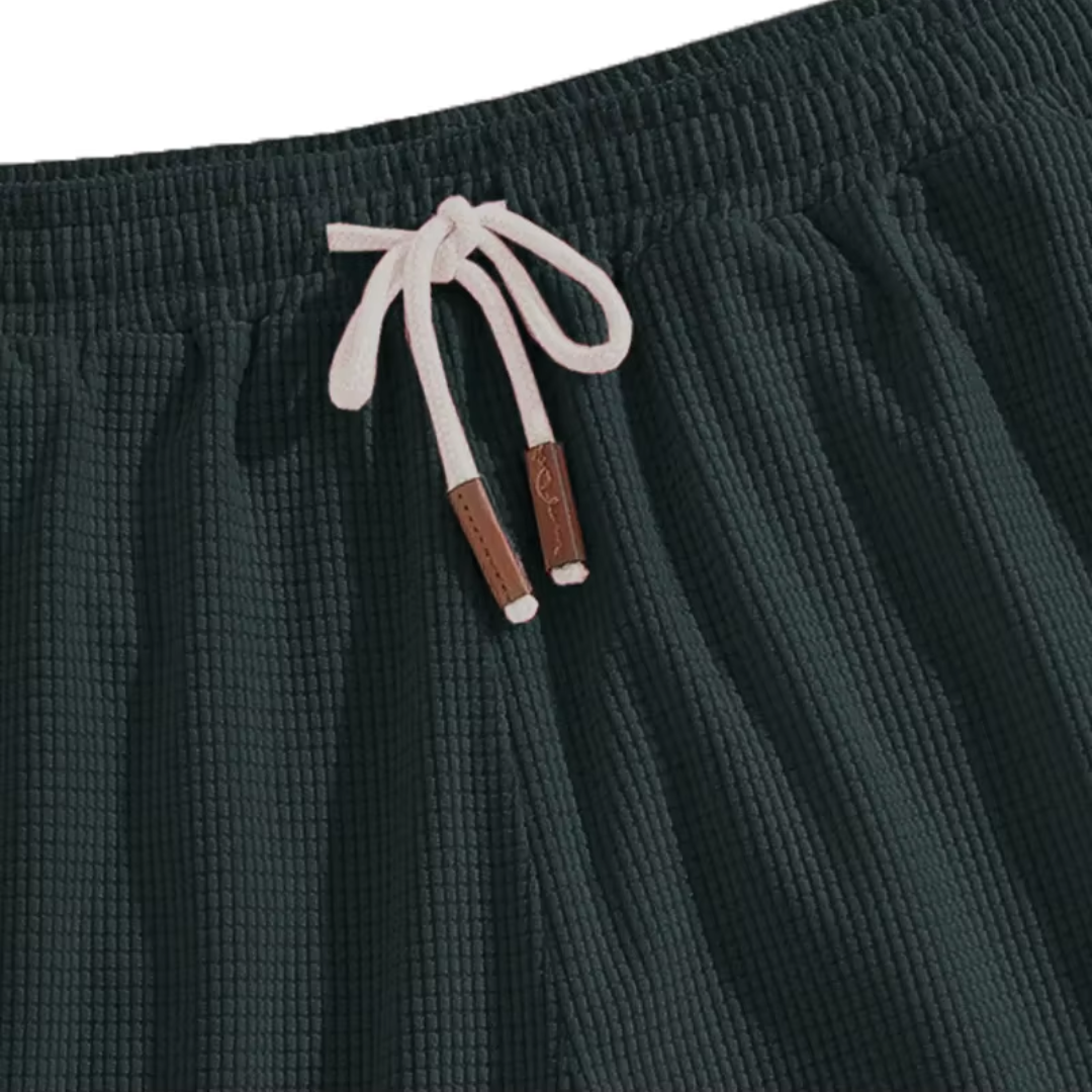 Dettaglio dei pantaloncini verde scuro con coulisse chiara e superficie a nido d'ape