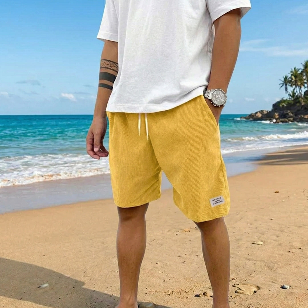 Pantaloncini uomo gialli a coste con coulisse bianca in vita, indossati in spiaggia