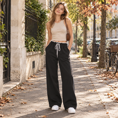 Pantaloni larghi neri con banda bianca laterale indossati con top beige corto