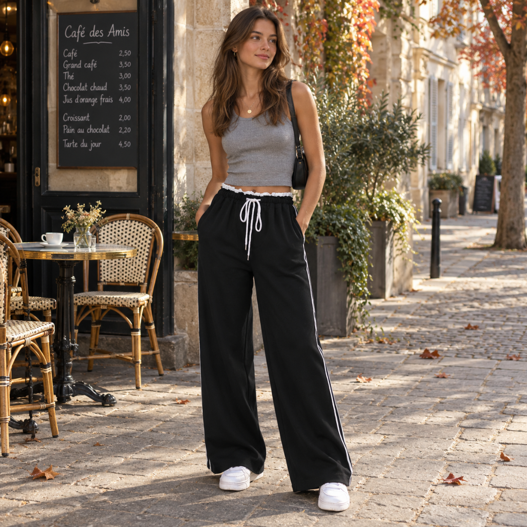 Pantaloni donna neri con bande bianche laterali e tasche, abbinati a canotta grigia