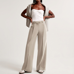 Look intero con pantaloni beige a gamba larga, top bianco e sneakers chiare