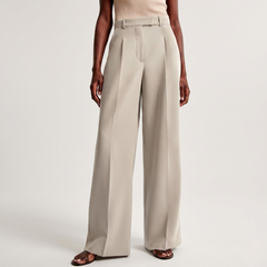 Dettaglio frontale dei pantaloni beige con piega stirata lungo tutta la gamba