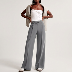Look completo con pantaloni grigio chiaro, top bianco e sneakers basse