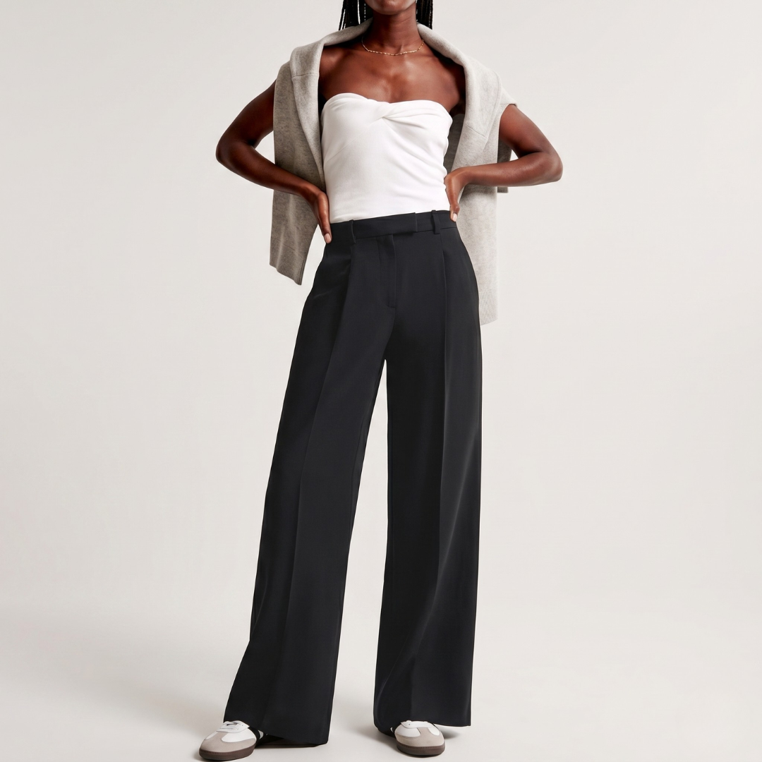 Outfit con pantaloni neri ampi, top bianco e sneakers chiare