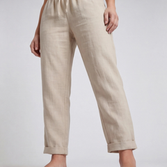 Pantaloni beige in primo piano sulla parte bassa, gamba affusolata e ampio risvolto