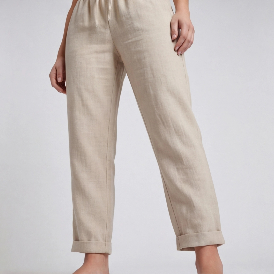 Pantaloni beige in primo piano sulla parte bassa, gamba affusolata e ampio risvolto