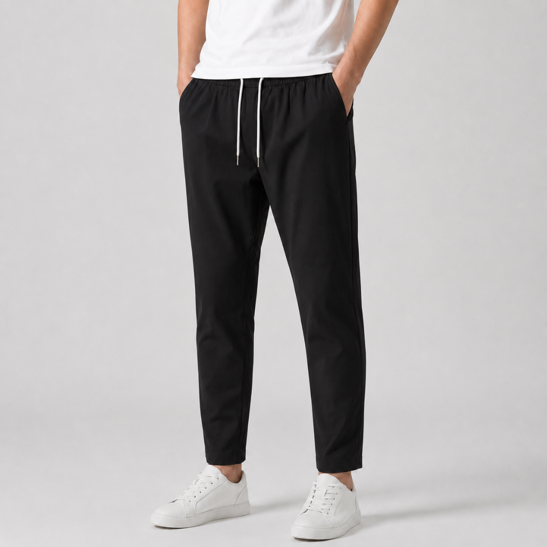 Pantaloni uomo neri affusolati con coulisse bianca a contrasto, abbinati a sneakers bianche