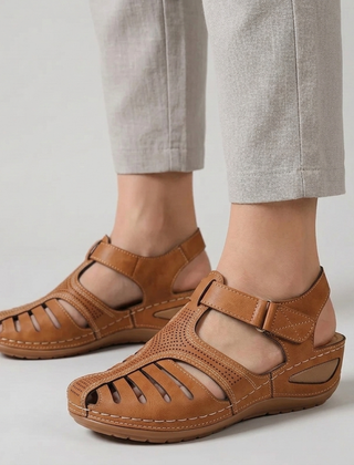 Sandali donna marroni traforati con cinturino regolabile indossati con pantaloni chiari