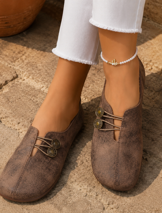 Scarpe basse donna marroni sfumate con bottoni decorativi, abbinate a pantaloni bianchi