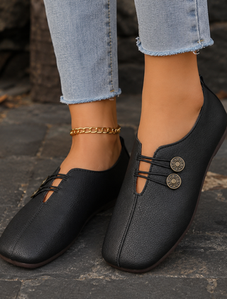 Scarpe basse donna nere con elastici incrociati, bottoni decorativi e punta arrotondata