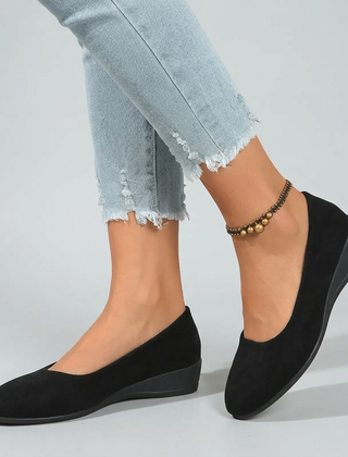 Scarpe donna nere slip-on con zeppa bassa abbinate a pantaloni sfrangiati chiari