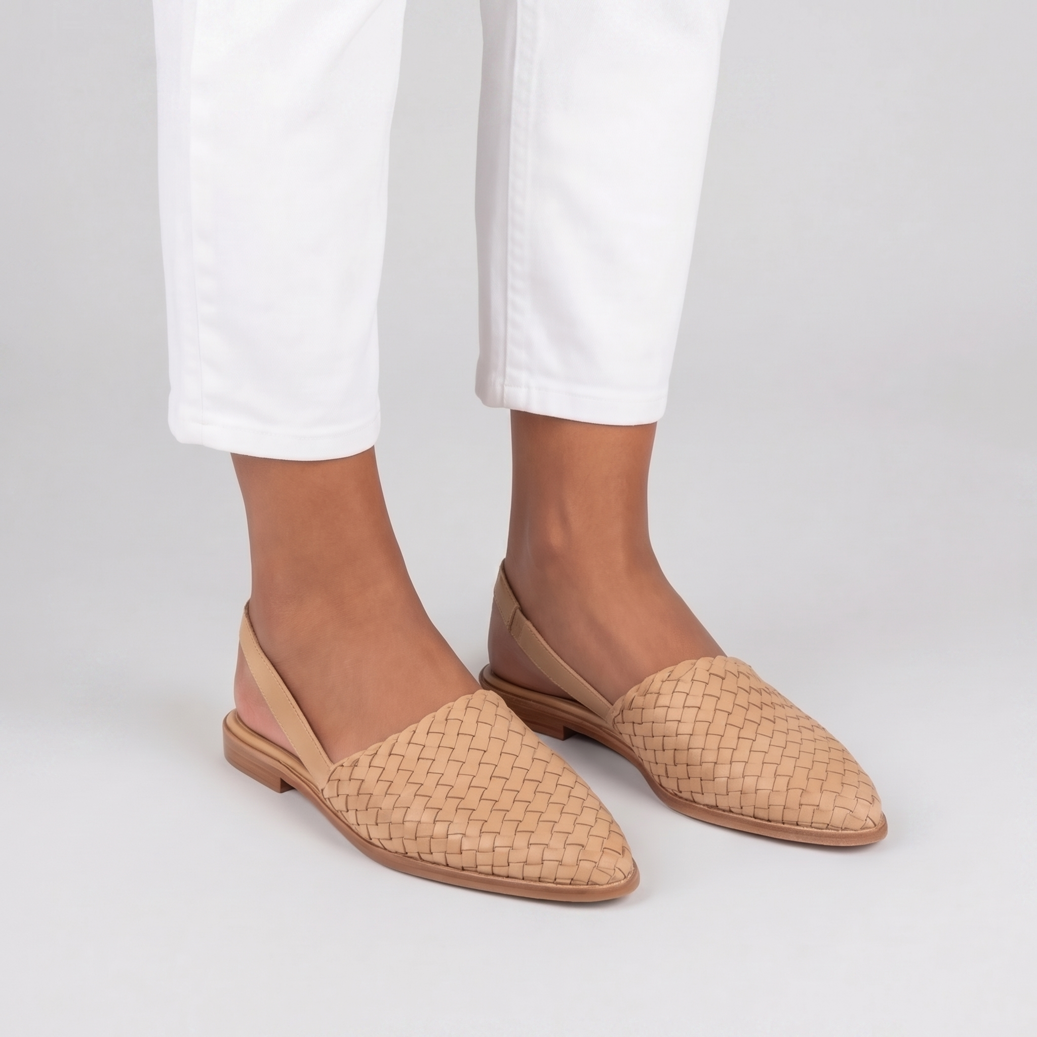 Slingback beige intrecciate con cinturino posteriore, indossate con pantaloni bianchi