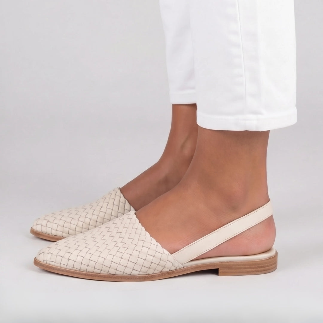 Dettaglio laterale delle slingback bianche con fascia posteriore morbida e tacco piatto