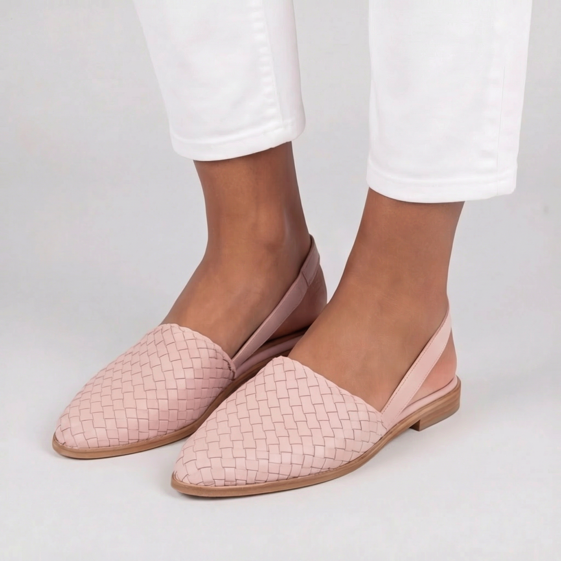 Slingback rosa intrecciate abbinate a pantaloni bianchi, con punta affusolata elegante