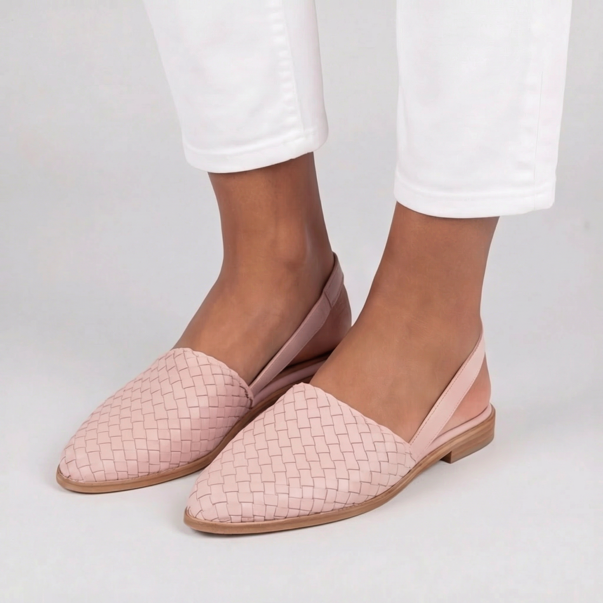 Slingback rosa intrecciate abbinate a pantaloni bianchi, con punta affusolata elegante