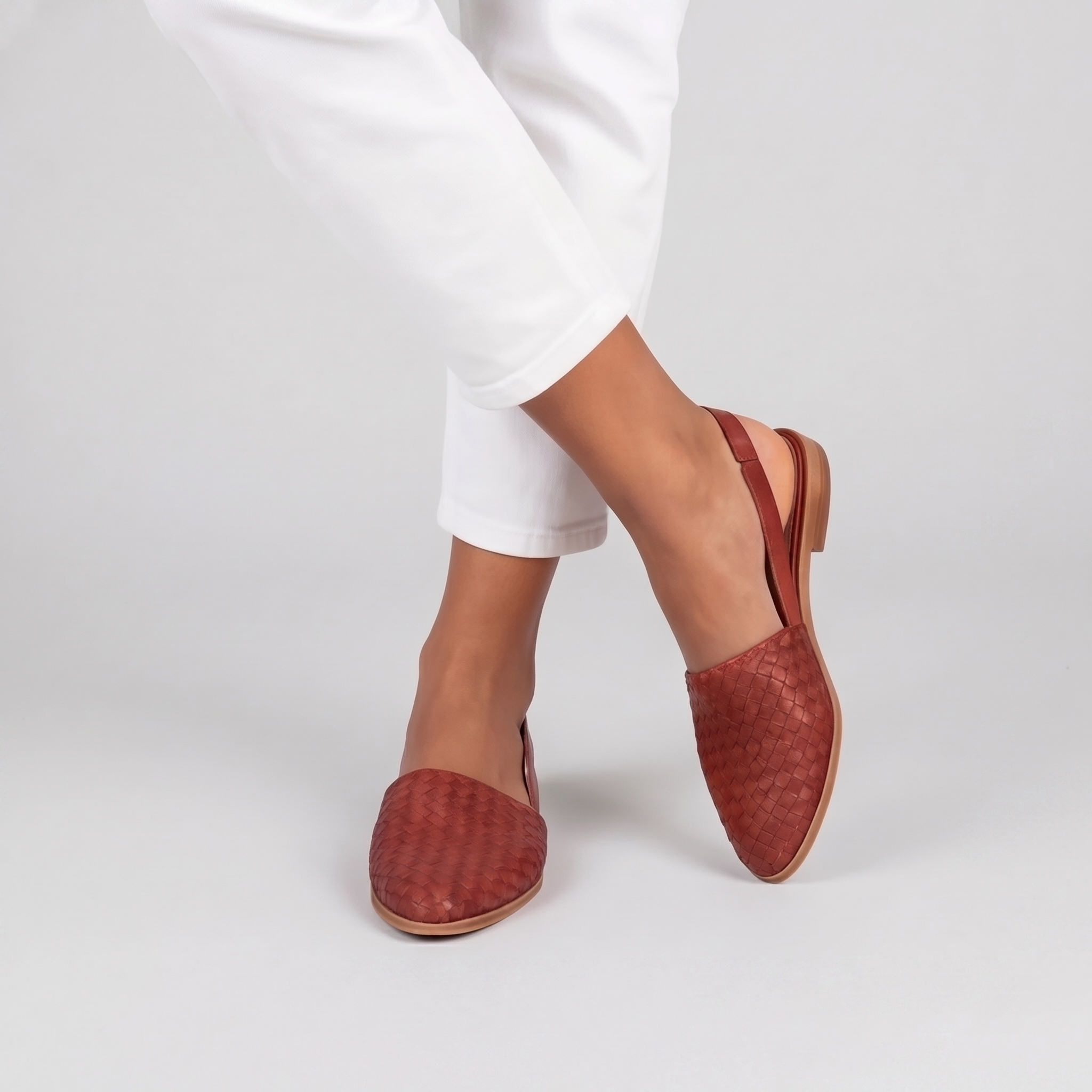 Slingback rosse in movimento con cinturino posteriore flessibile e tomaia intrecciata