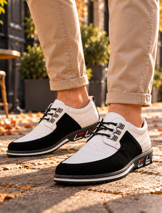 Scarpe stringate uomo bianco e nero con ganci metallici indossate su pavé