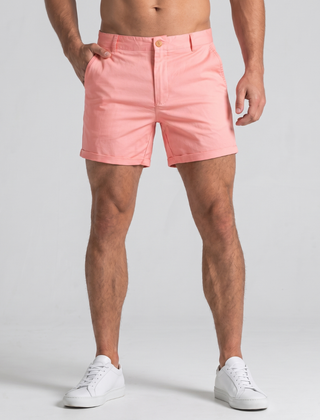 Shorts uomo rosa con orlo risvoltato e tasche laterali, abbinati a sneakers bianche