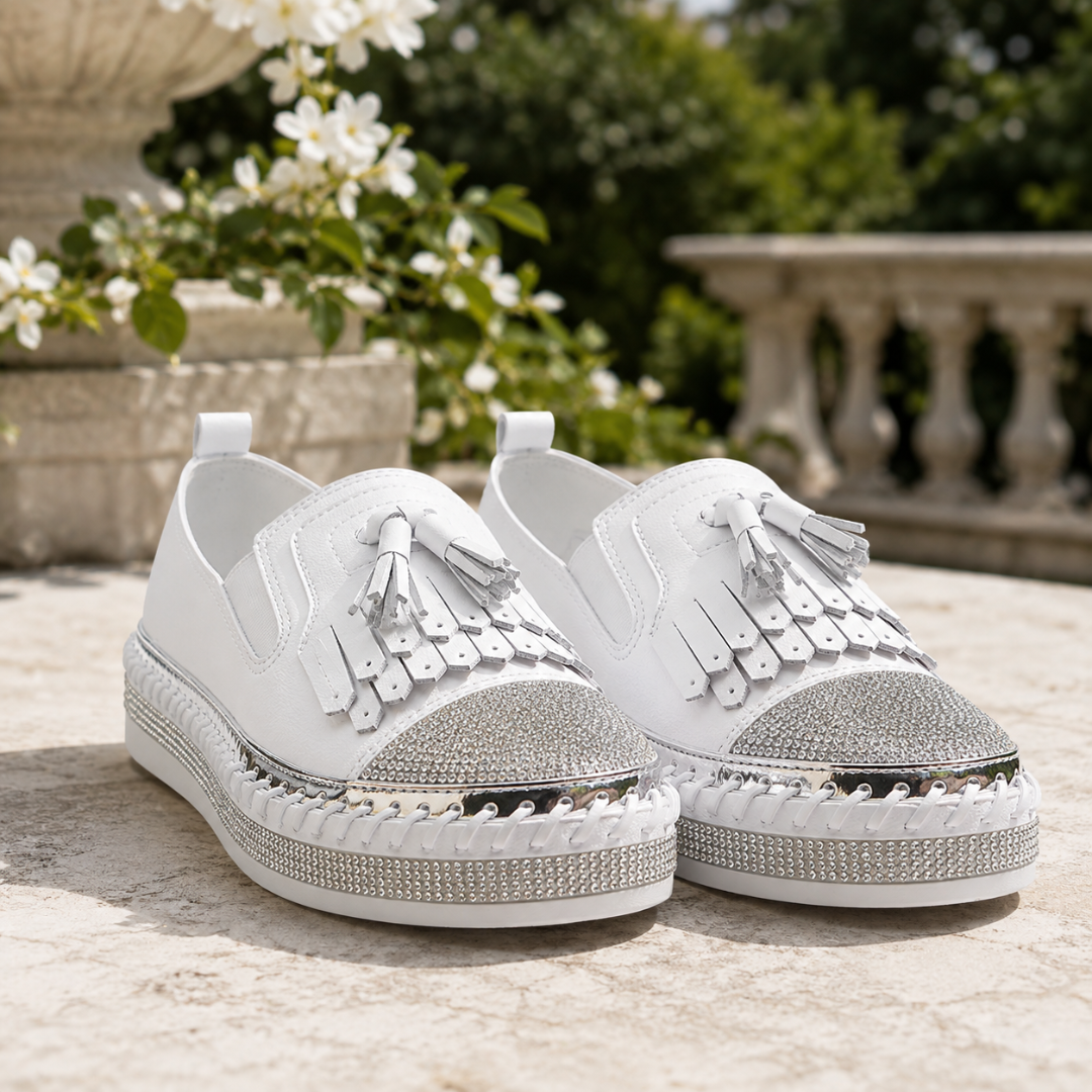 Sneakers bianche viste di fronte con nappine, suola platform intrecciata e bordo metallico