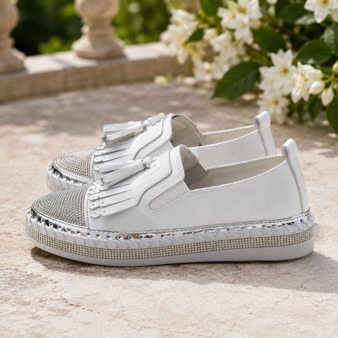Dettaglio delle sneakers bianche con linguetta posteriore e suola platform con strass