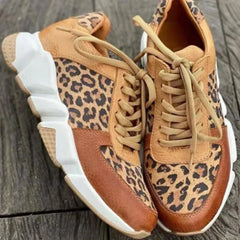 Paio di sneakers leopardate cammello appoggiate su legno, suola scolpita ben visibile