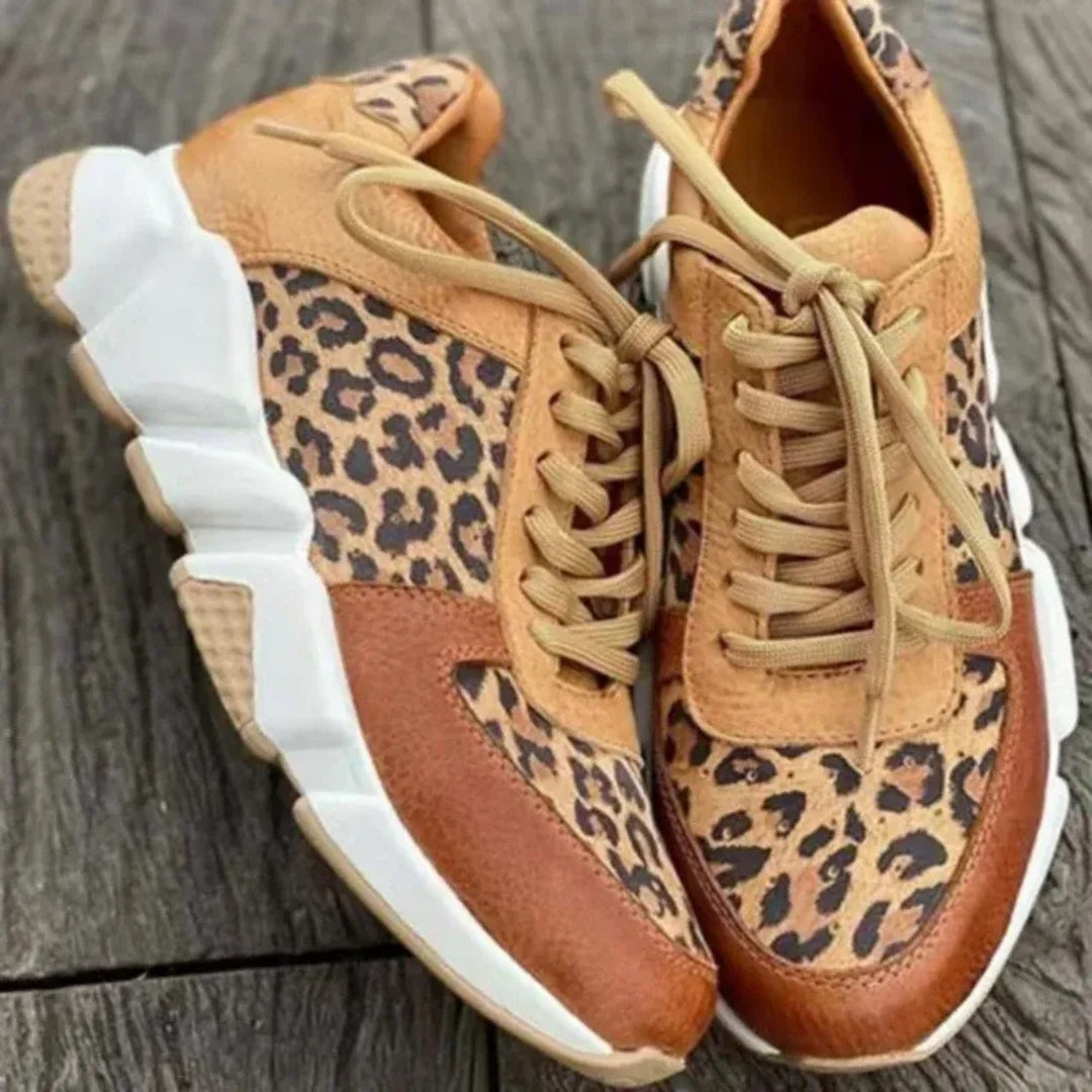 Paio di sneakers leopardate cammello appoggiate su legno, suola scolpita ben visibile