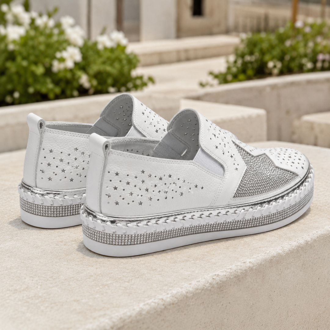 Vista posteriore delle sneakers bianche con perforazioni a stella e linguetta al tallone