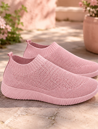 Sneakers slip on rosa traforate con suola bassa rigata su pavimento in pietra