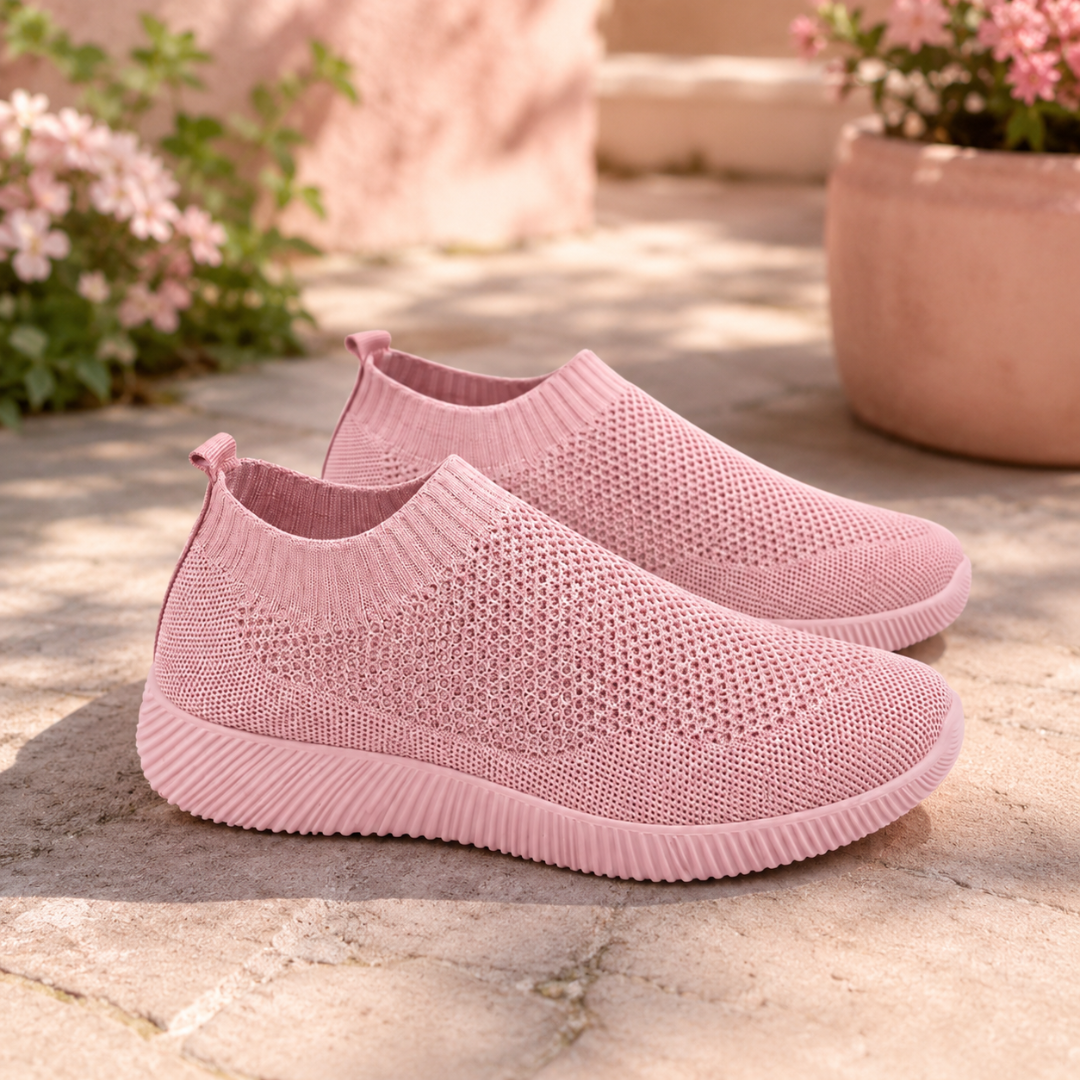 Sneakers slip on rosa traforate con suola bassa rigata su pavimento in pietra