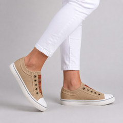 Sneakers beige senza lacci viste di lato con occhielli brunati e fondo bianco flessibile