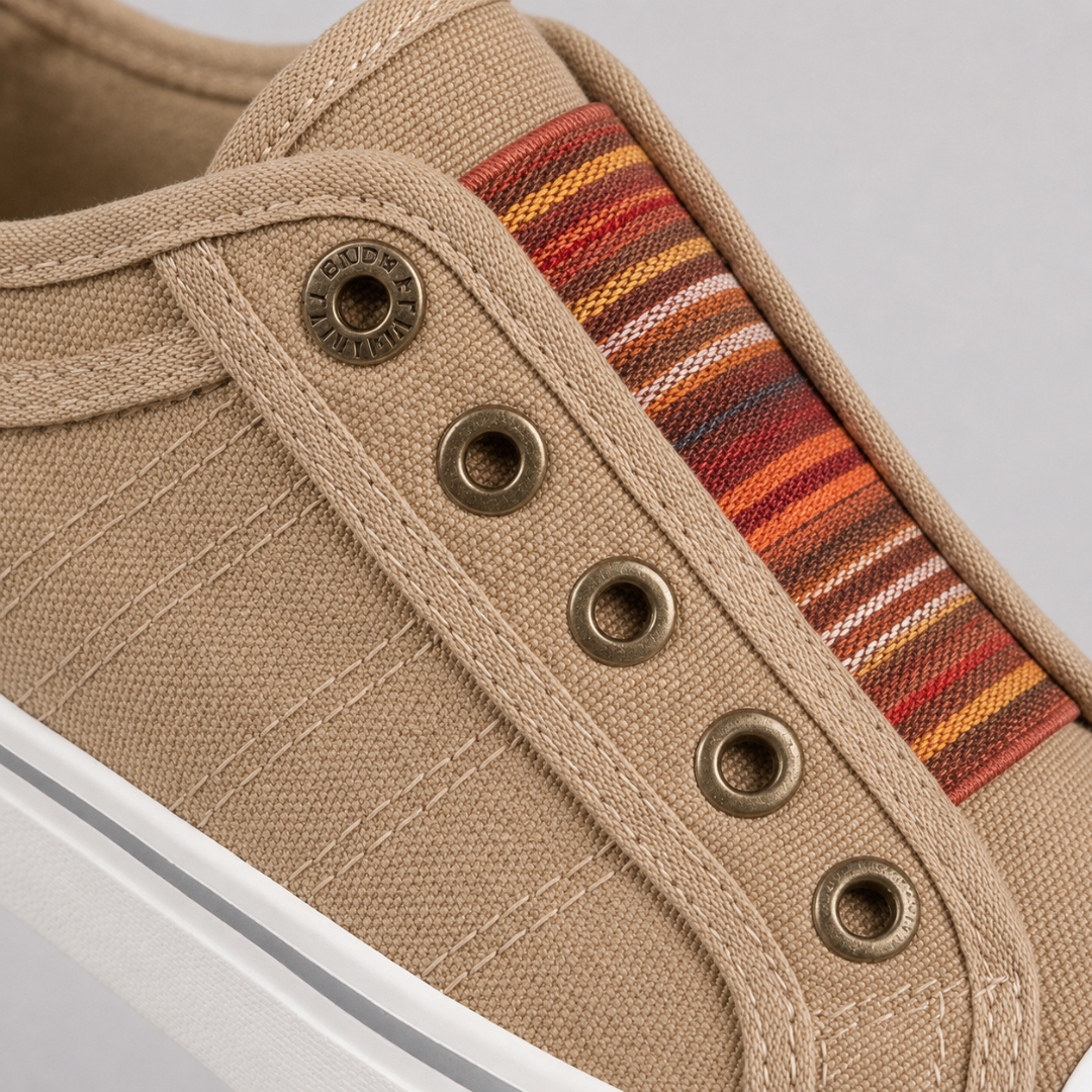 Dettaglio della sneaker beige con inserto elastico a righe multicolore e occhielli metallici