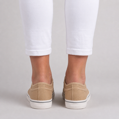 Retro delle sneakers beige indossate, talloncino basso e bordino grigio sul fondo bianco